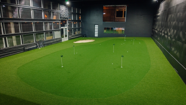 Iekštelpu golfa treniņu zāle ar mākslīgo zālienu, ripināšanas bedrītēm un apgaismotu telpu
